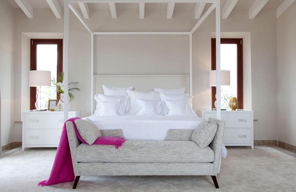 A light and airy coastal bedroom design using white bedding and a pop of colour four poster bed