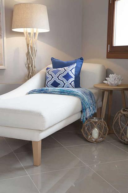 An elegant cream chaise lounge with blue cushions and throw and driftwood lamp
