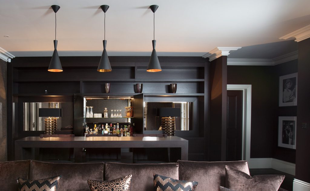 Moody and masculine entertainment snug room with bespoke cocktail home bar and large chocolate velvet sofa